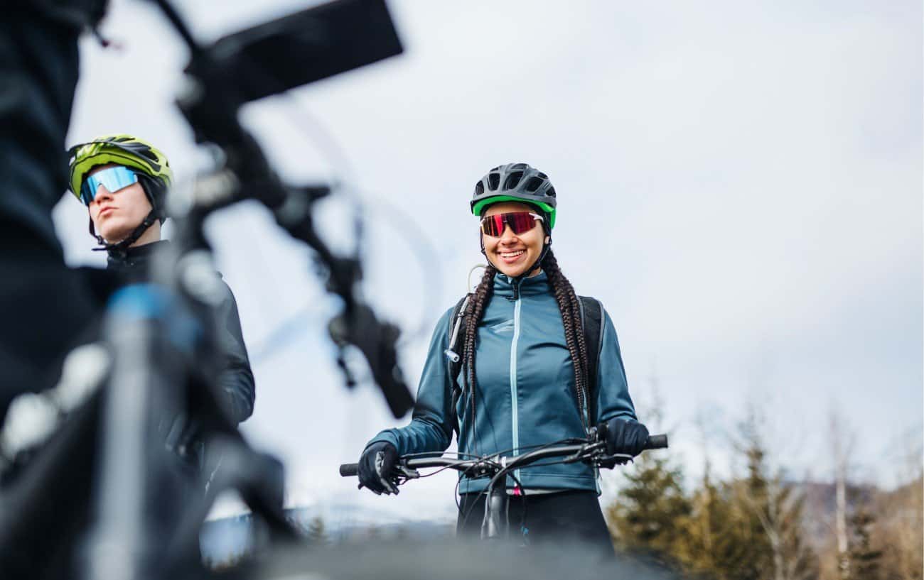 A cyclist waits on her bike on an overcast day.