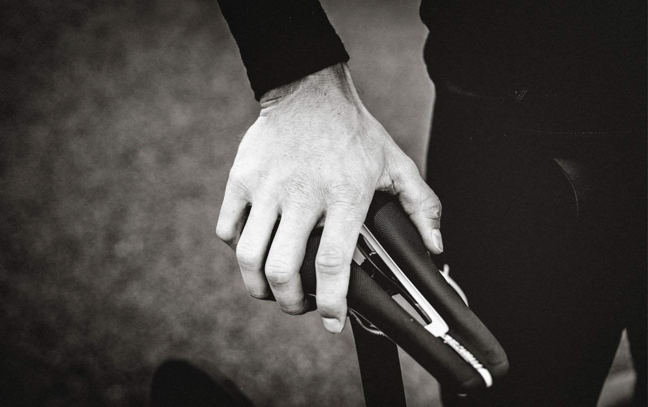 Black and white photo of a mans hand on a bike saddle.