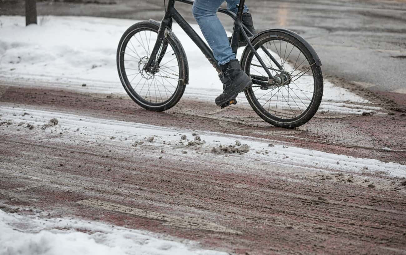 A cyclist rides through slushy snow.