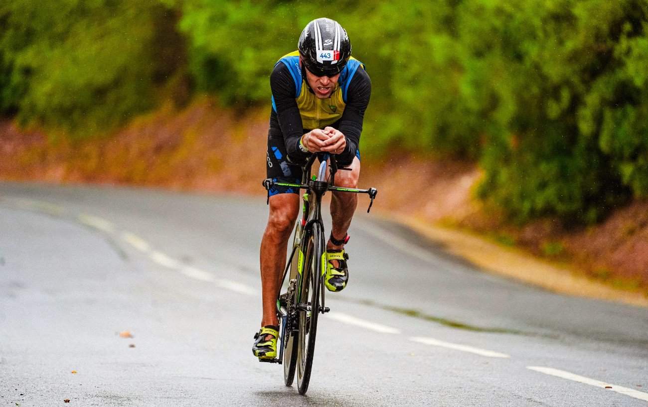 A cyclist descends a tarmac road on a bike fitted with integrated aero bars.