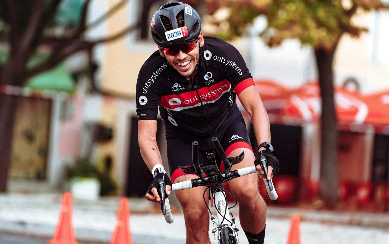 A triathlete rides a white bike fitted with clip-on aero bars.