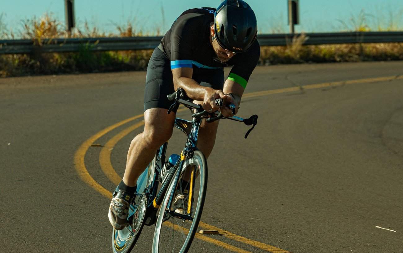 A cyclist rides a black bike with aero bars fitted.