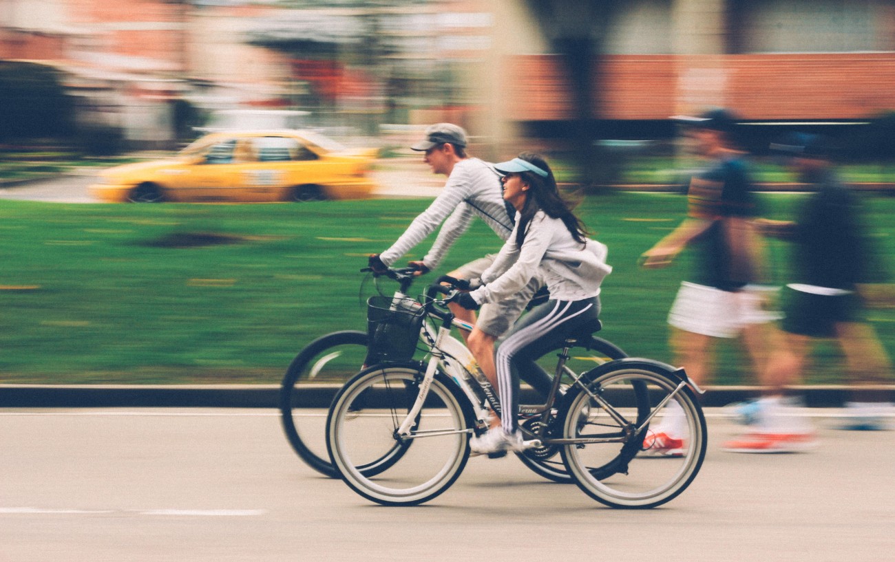 Two cyclists ride together through the city.