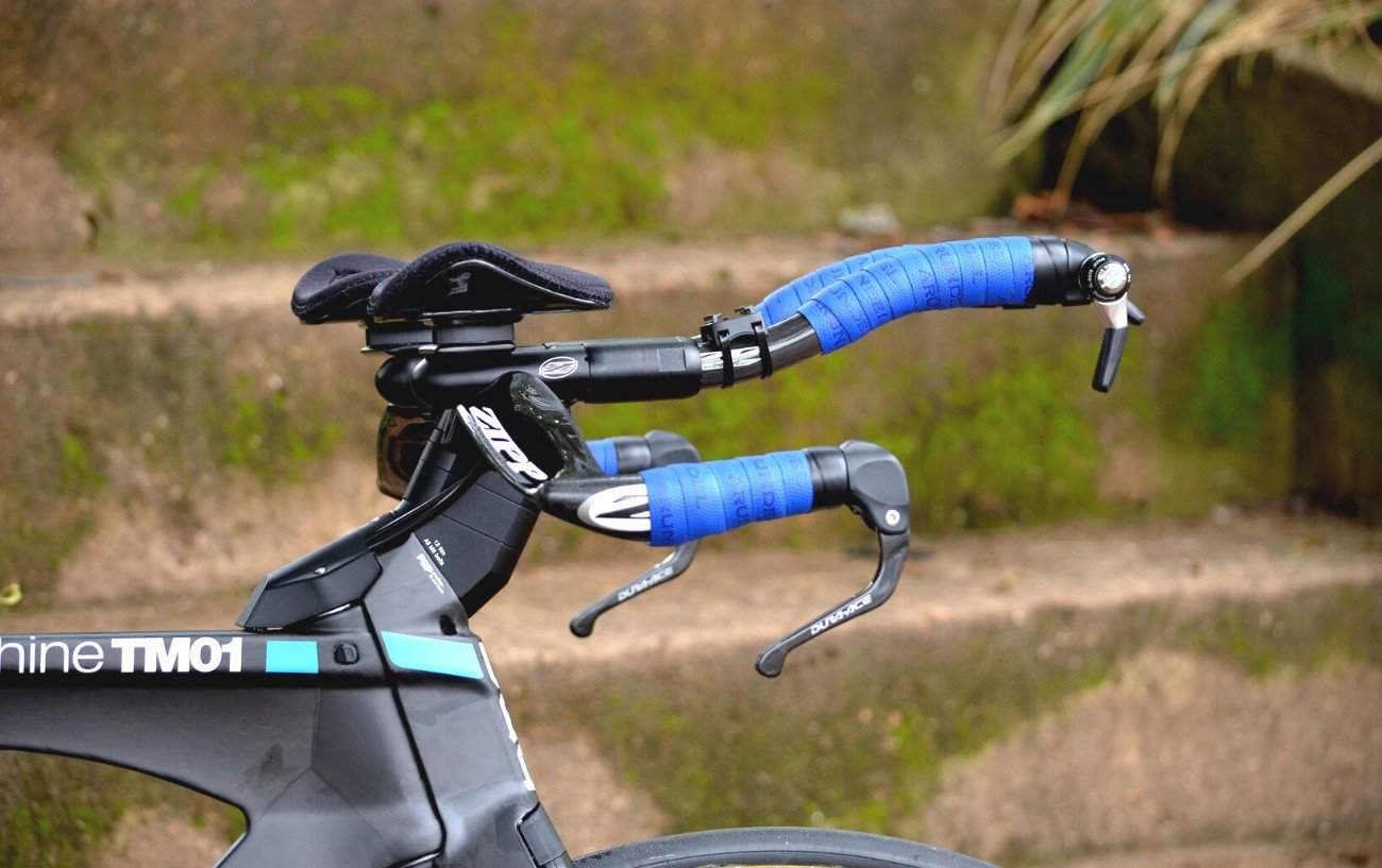 Aero bars with blue griptape, attached to a black time-trial bike.