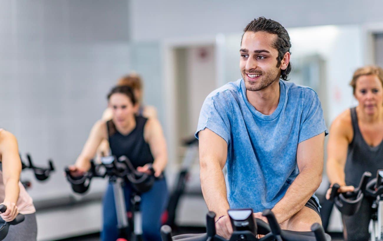 Man leads a group of riders on exercise bikes.