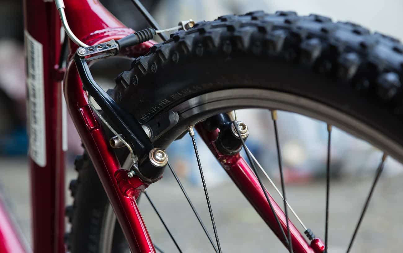 Close-up of rim brakes on a red bike.