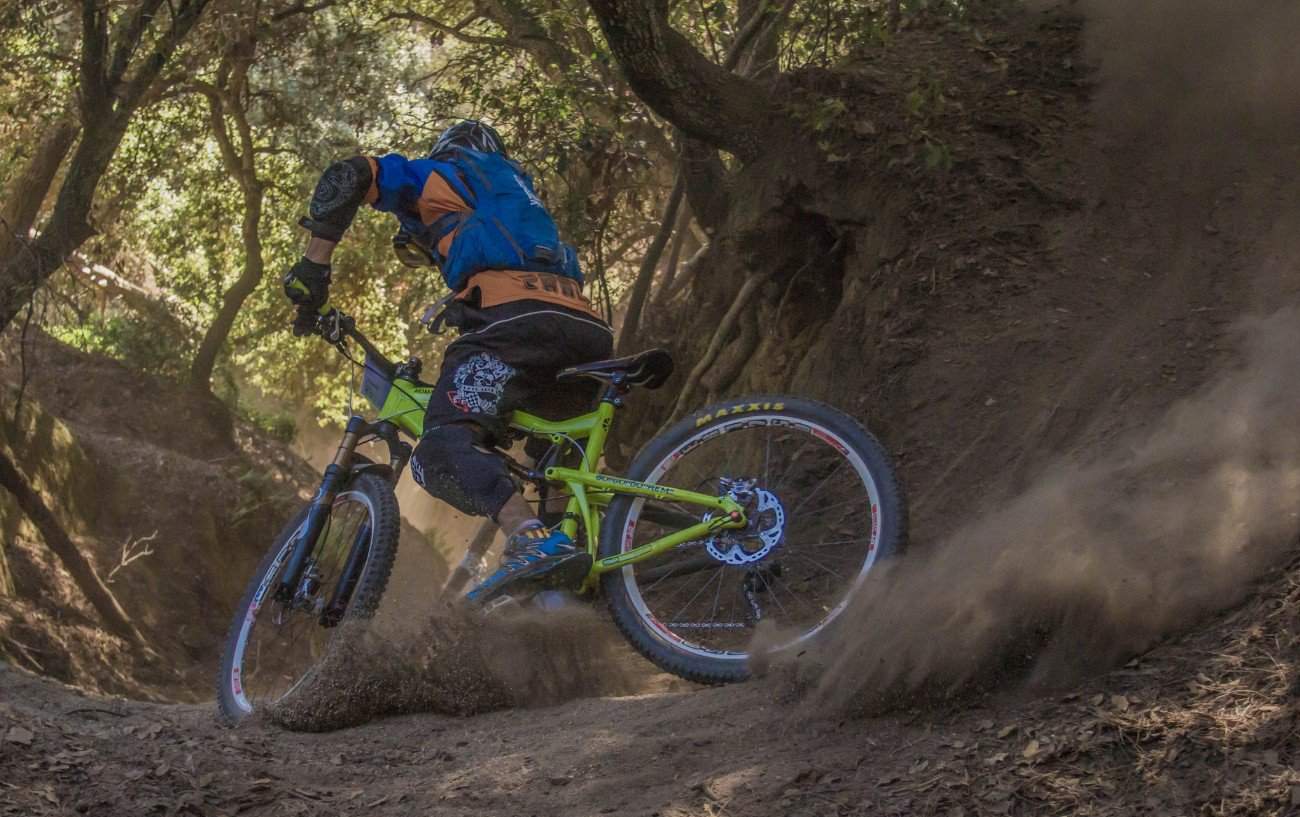 A mountain biker drifts round a corner on a dirt track.