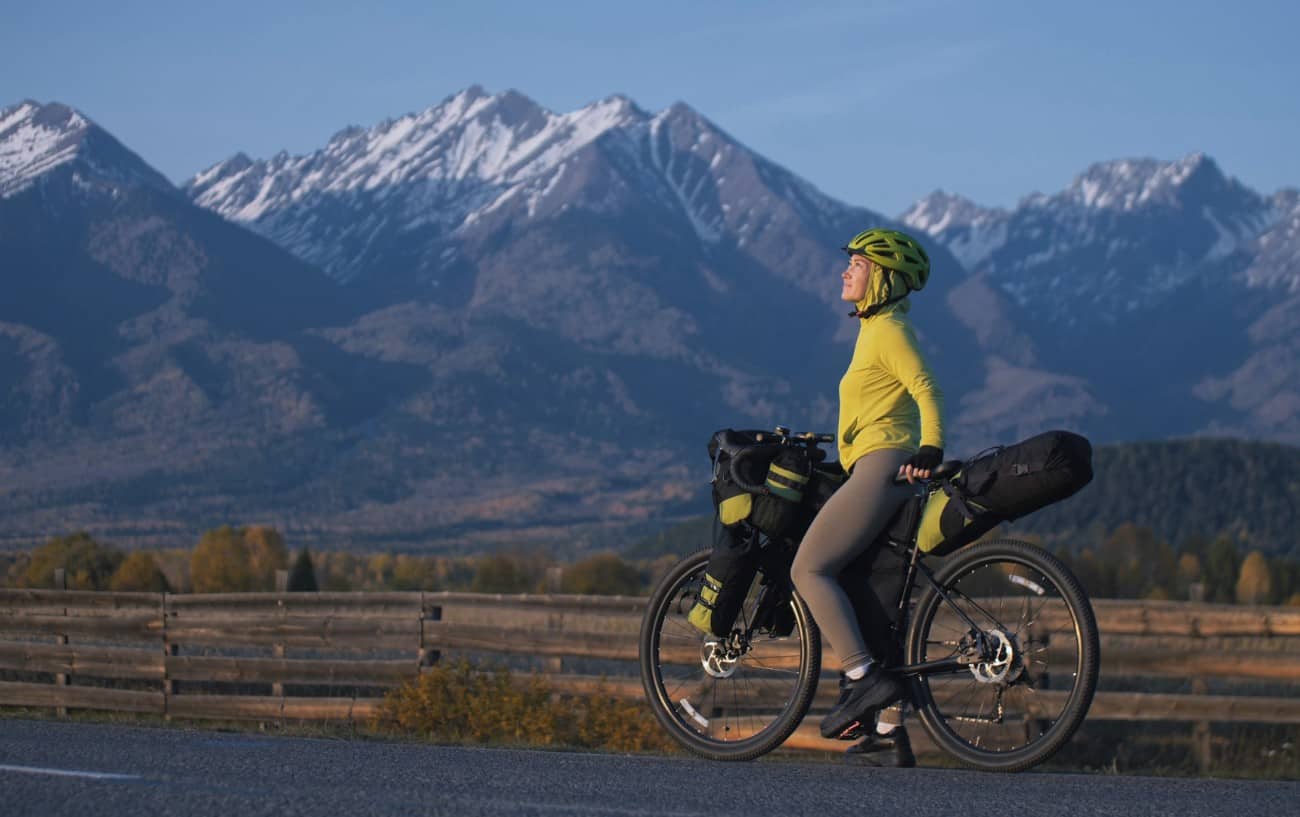 A bikepacker pauses to admire the views in a mountainous valley.