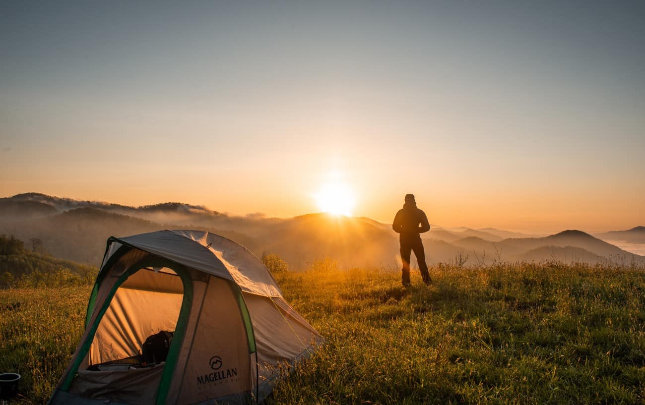 A bikepacker leaves their tent at sunrise.