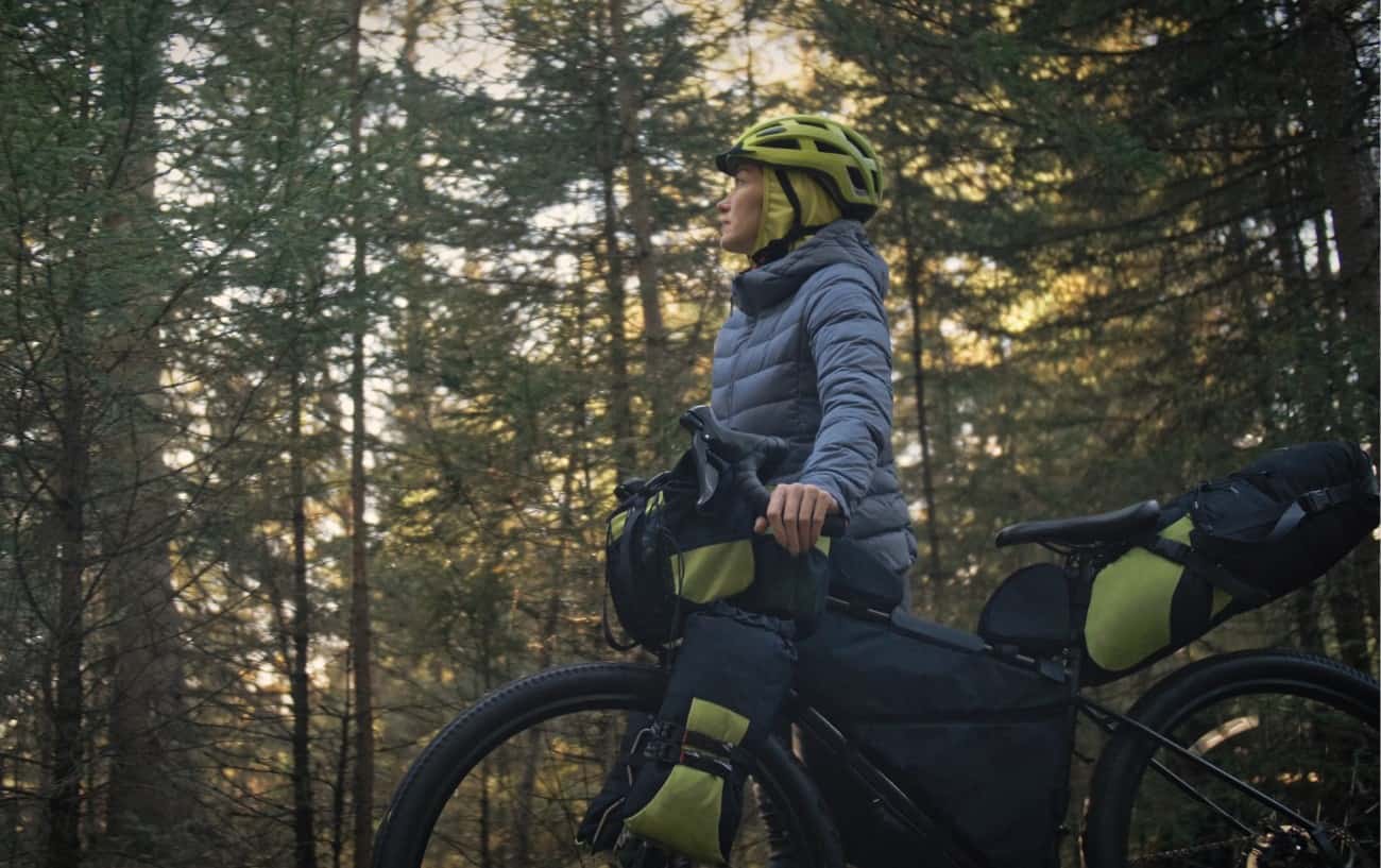 A bikepacker pauses in a forest in spring.