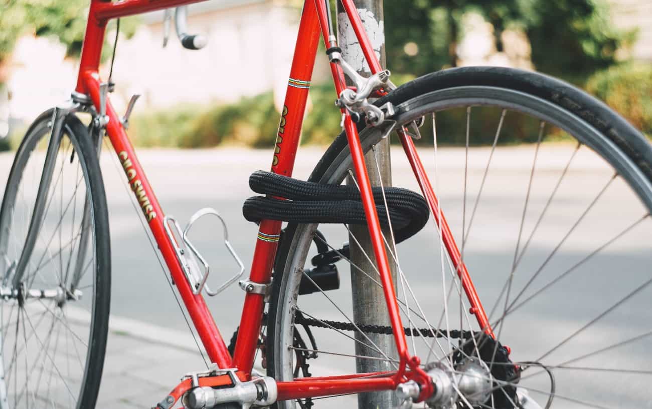 A red road bike locked up on the street.