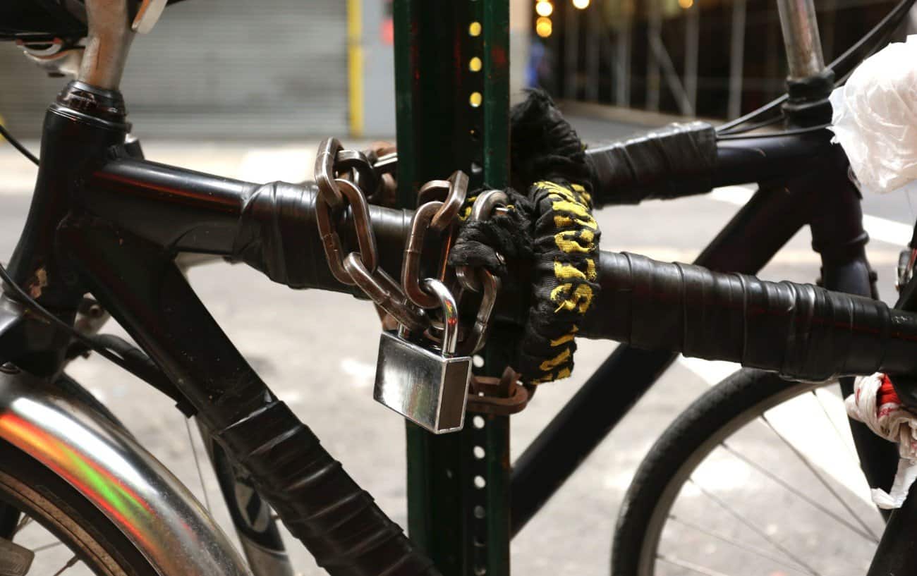 Black bike with a heavy-duty padlock wrapped around it.