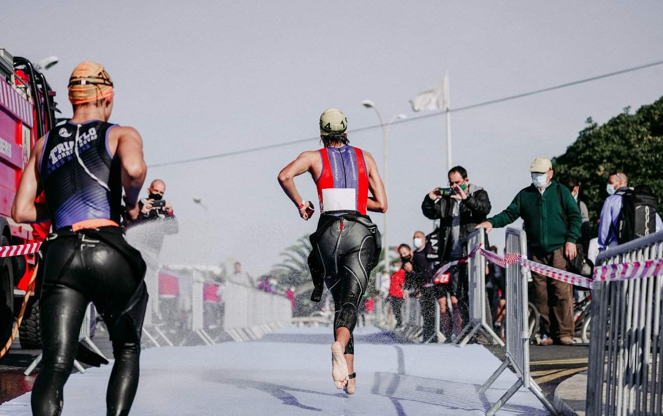 Two triathletes run through a transition section.