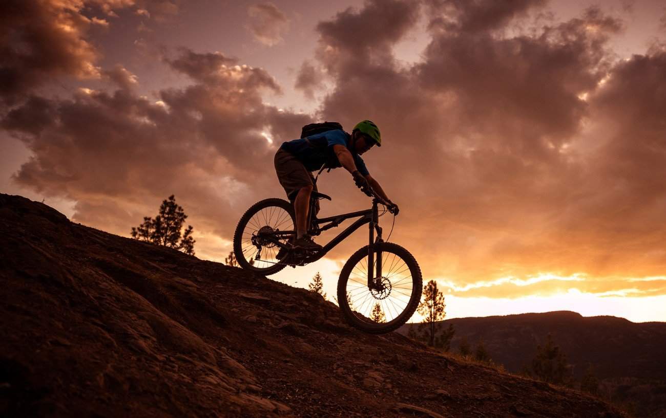 A mountain bike descends a rocky trail at sunset.