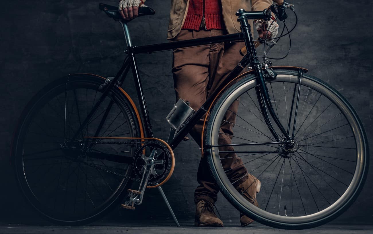 A black single-speed bike in a photographer's studio, with a grey slate background behind.