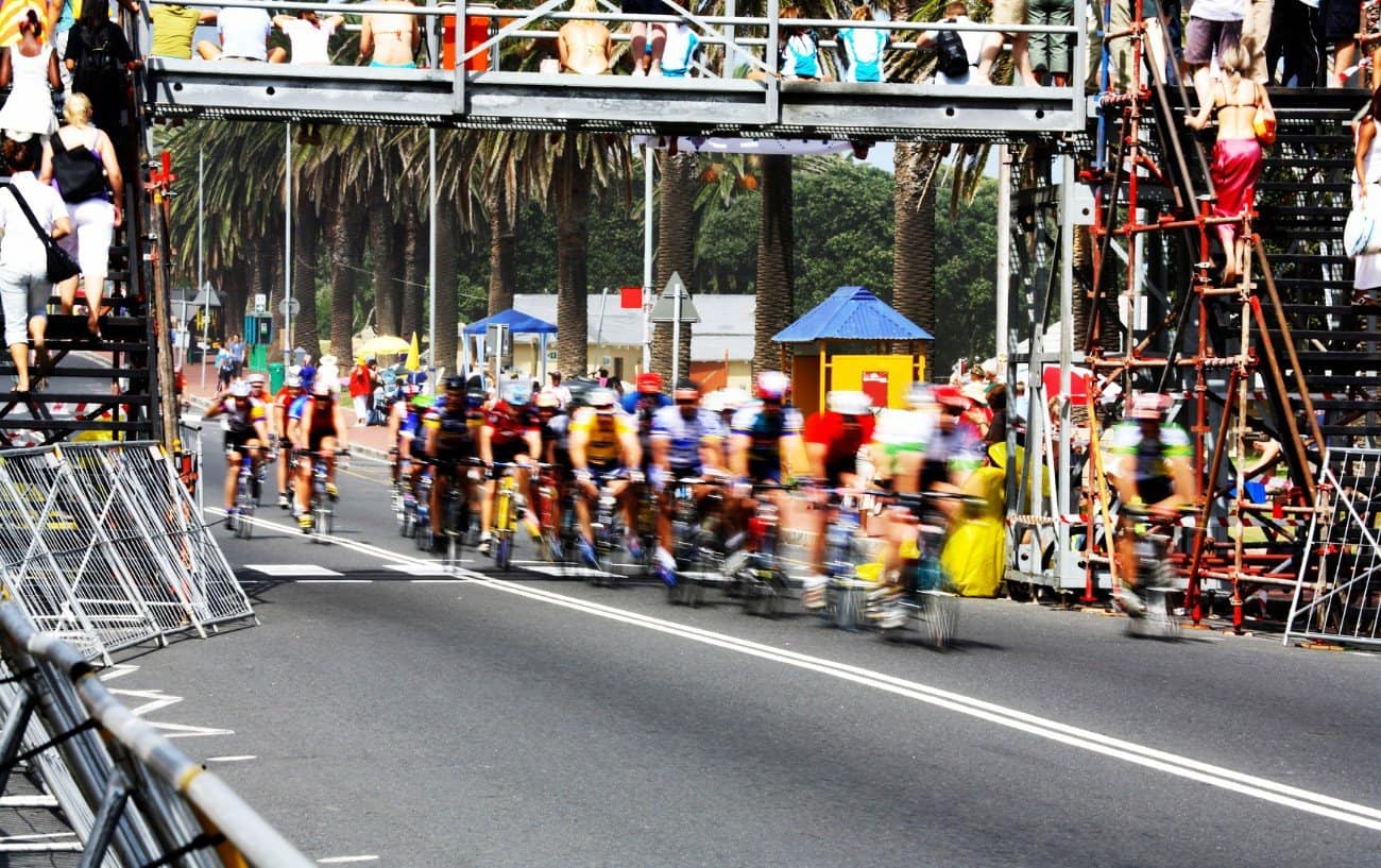 A group of cyclists race through a finish line.