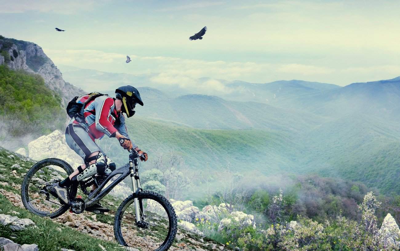 A mountain bikes descends a trail into a misty valley.