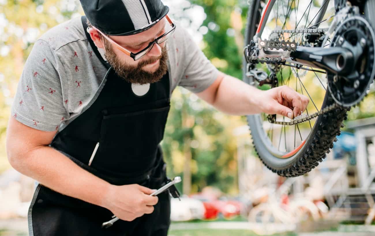 A bike mechanic uses a chain gauge to check a bike chain.