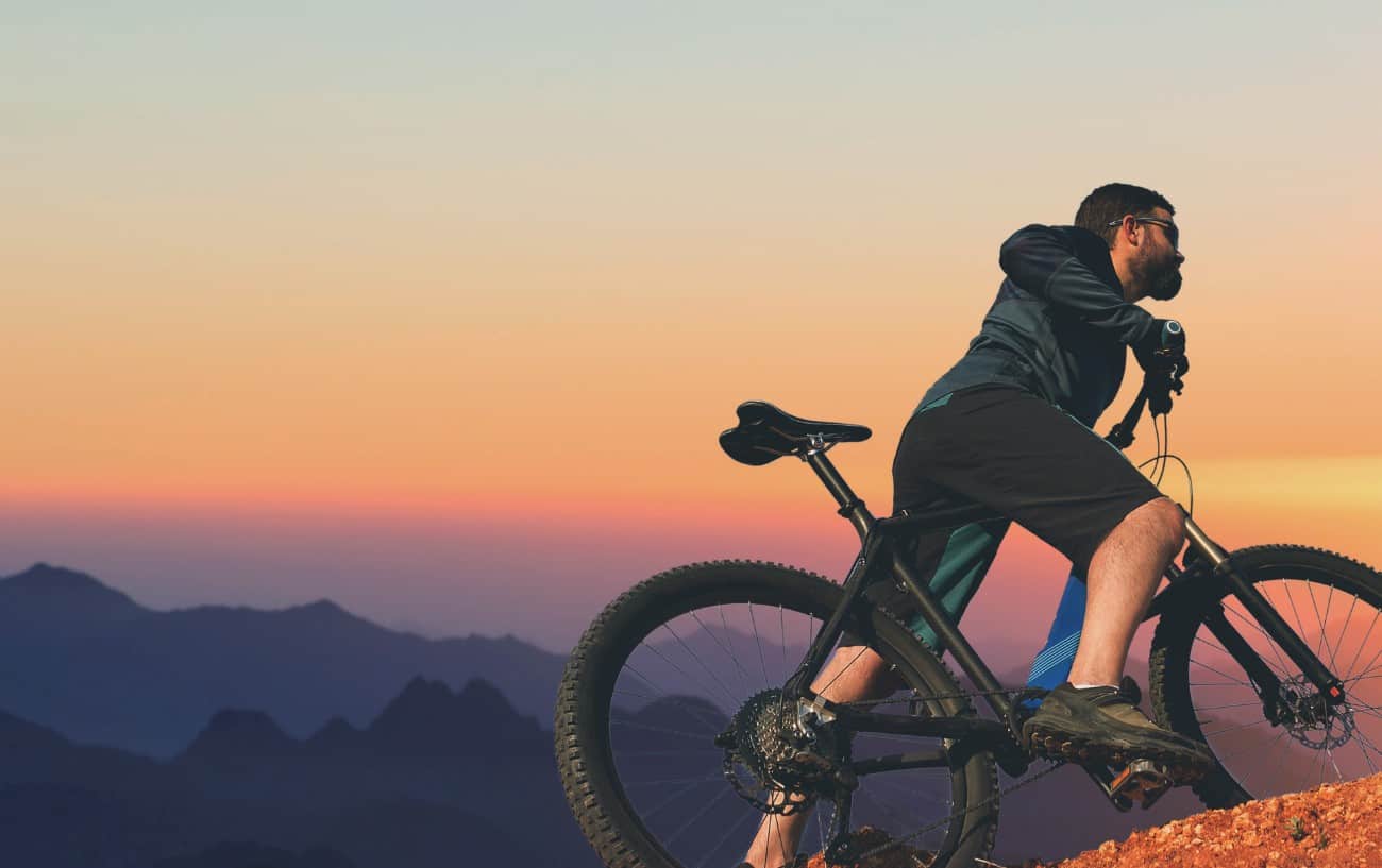 A cyclist rides a hardtail mountain bike at sunset.