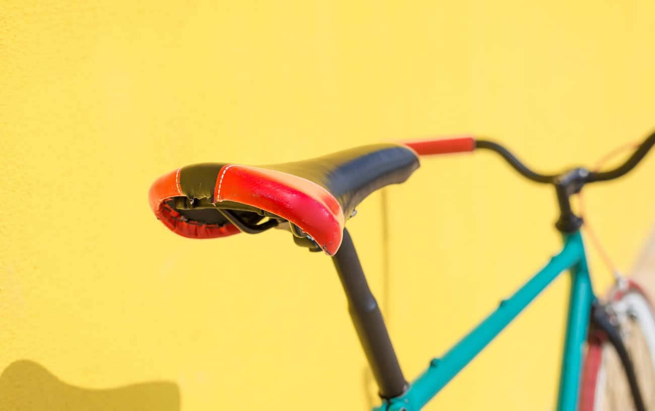 A green city bike leans against a yellow wall.