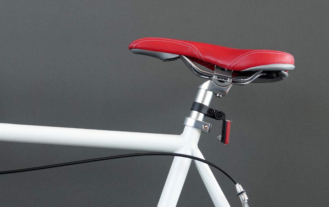 Close-up of a white racing bike with a red leather seat.