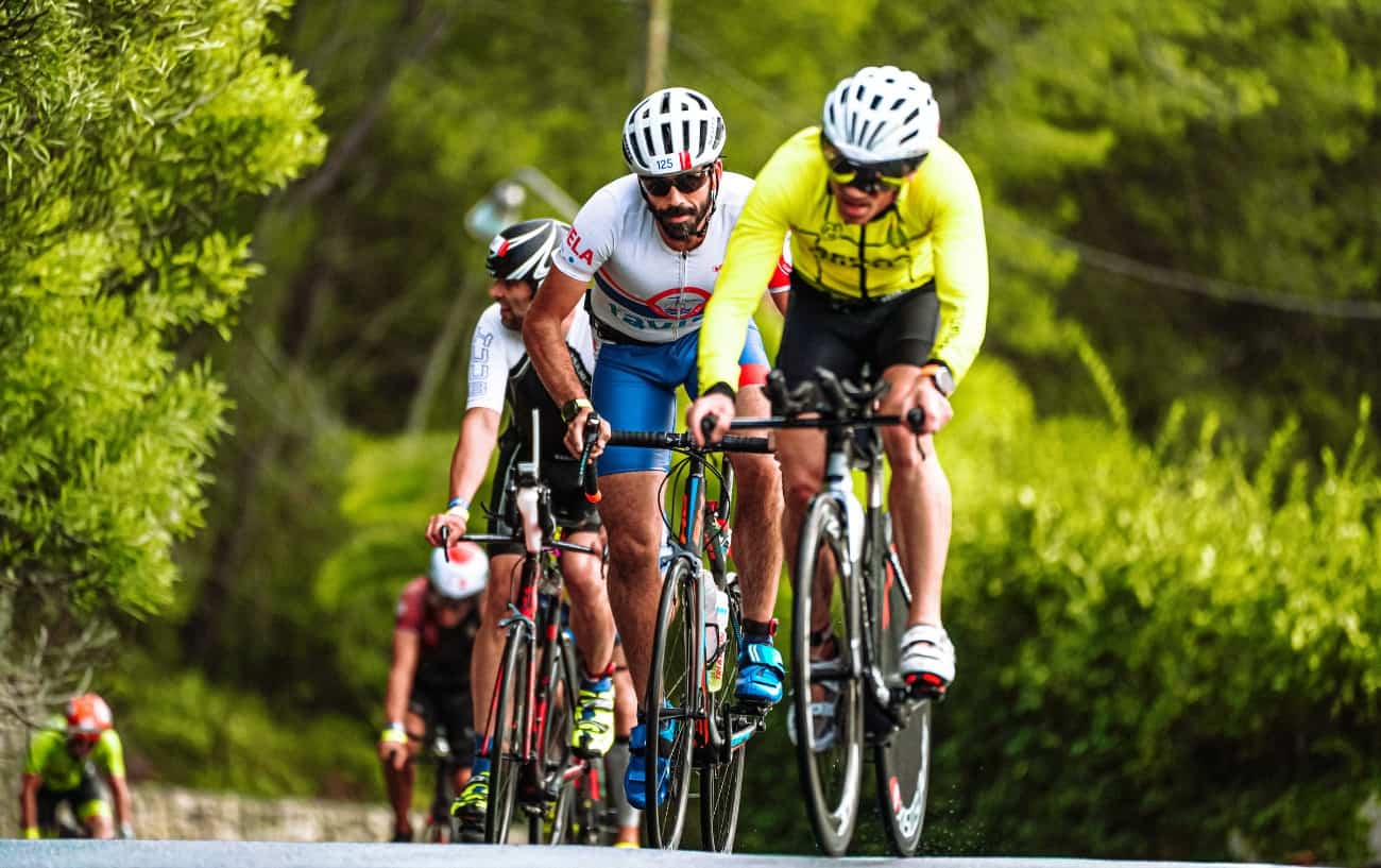 A group of road cyclists race each other up a steep climb.
