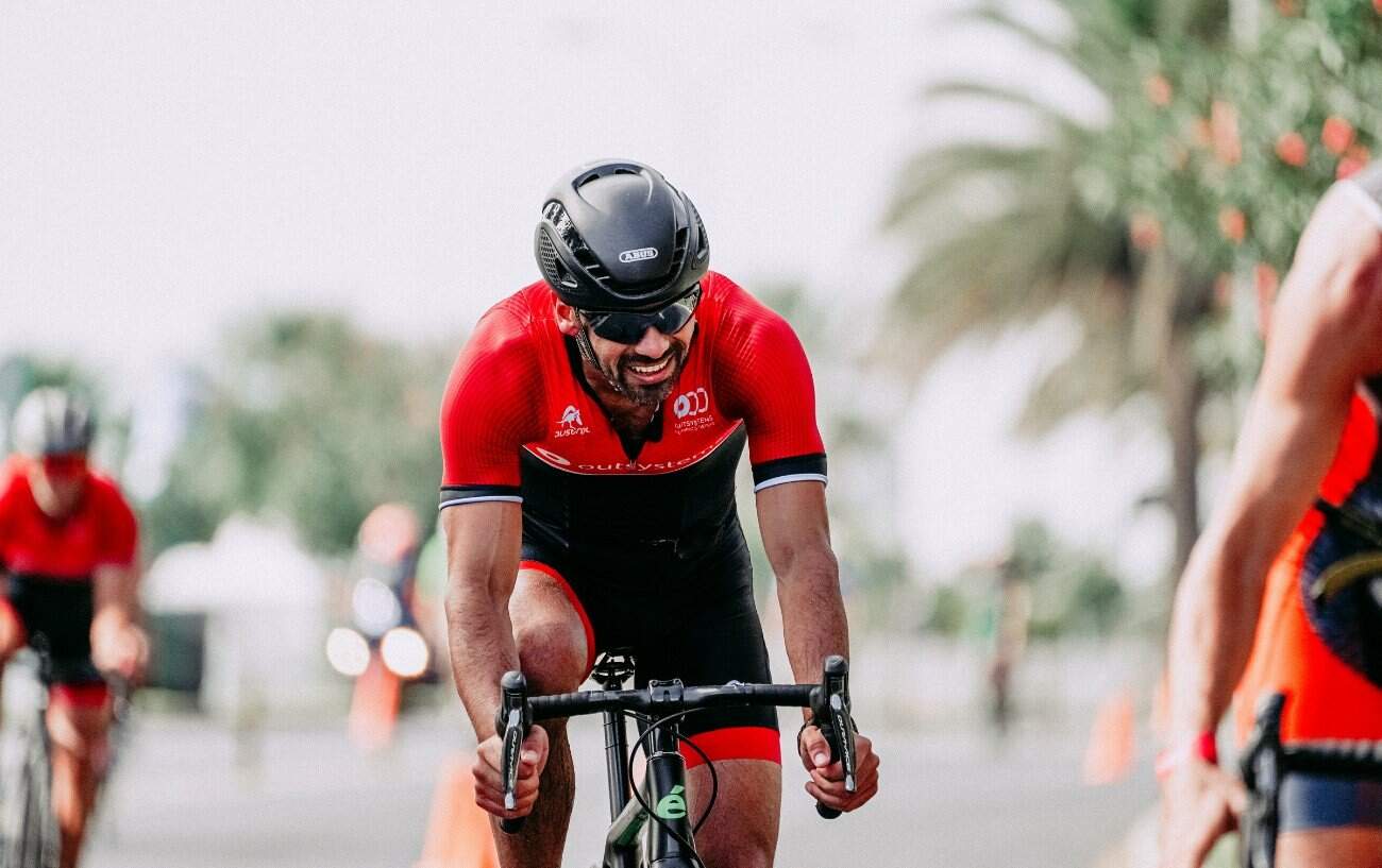 A cyclist in a red jersey crosses a finish line.