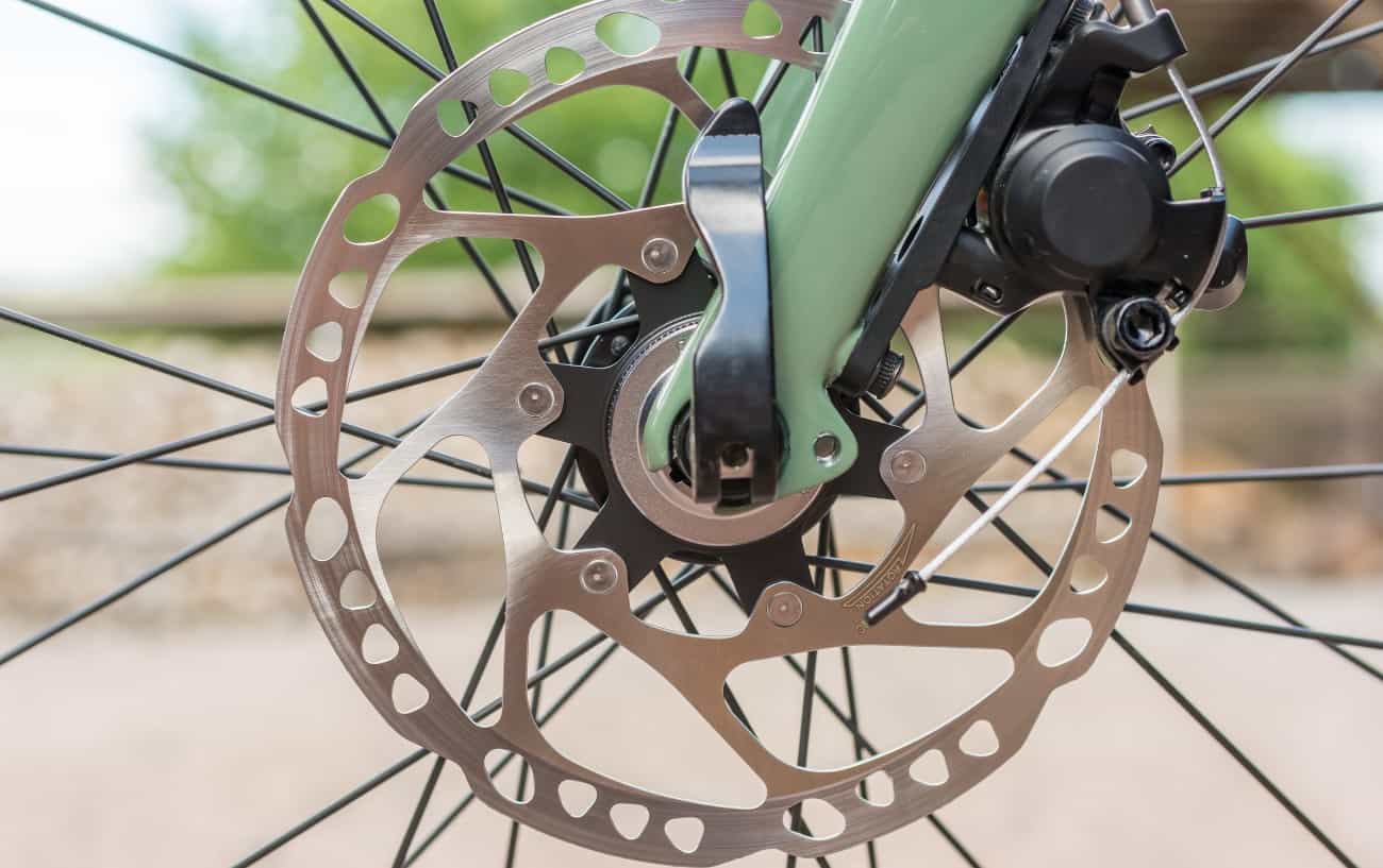 Pale green bike fork, fitted with disc brakes and a thru axle.