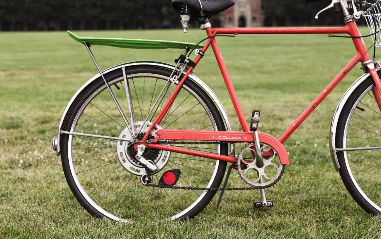 A red hybrid bike sits on a grassy lawn.