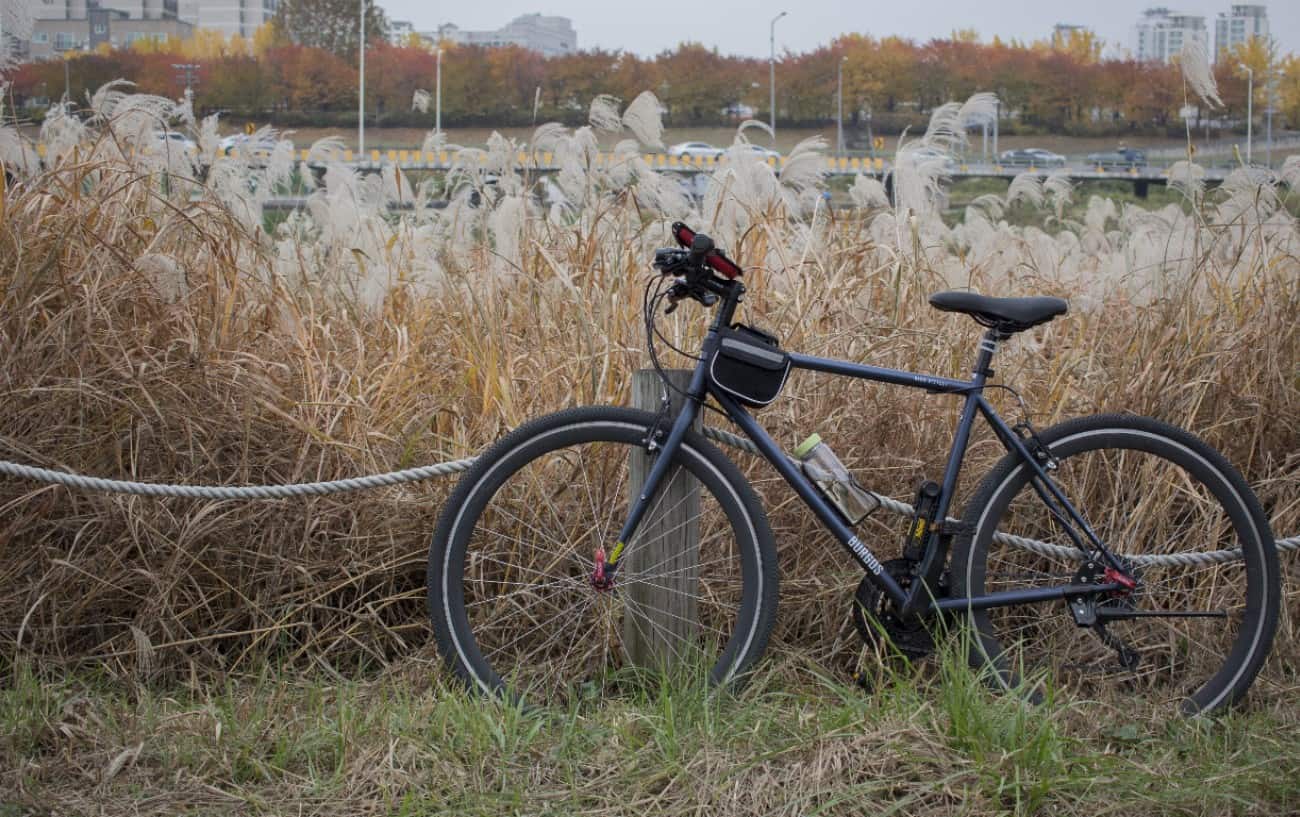 A black hybrid bike leans against a wooden post.