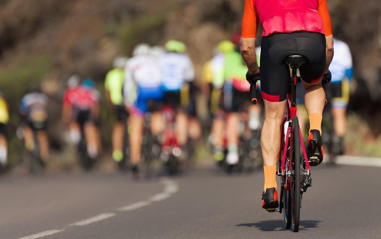 Rear-view of a cyclist on a pink road bike chasing the pack ahead.