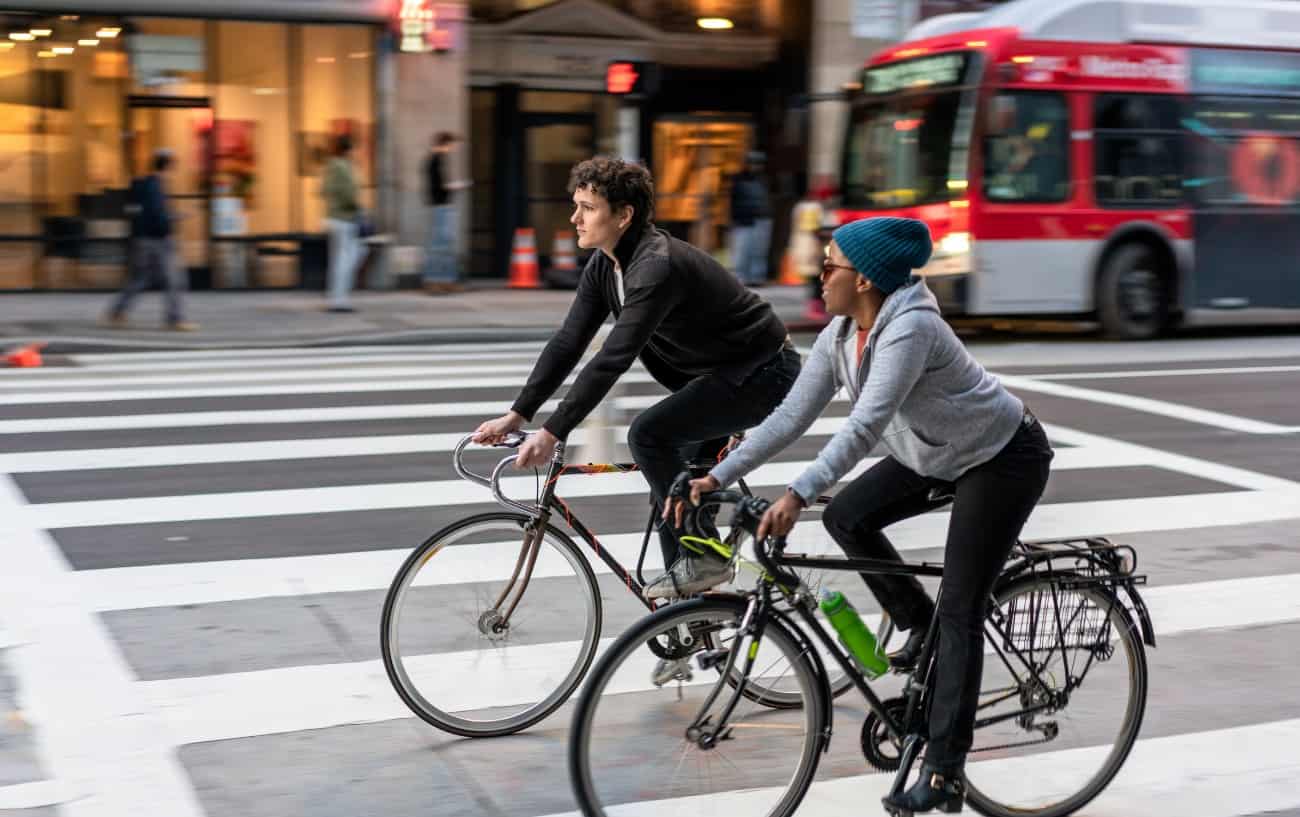 Two cyclists ride through a US city without helmets.