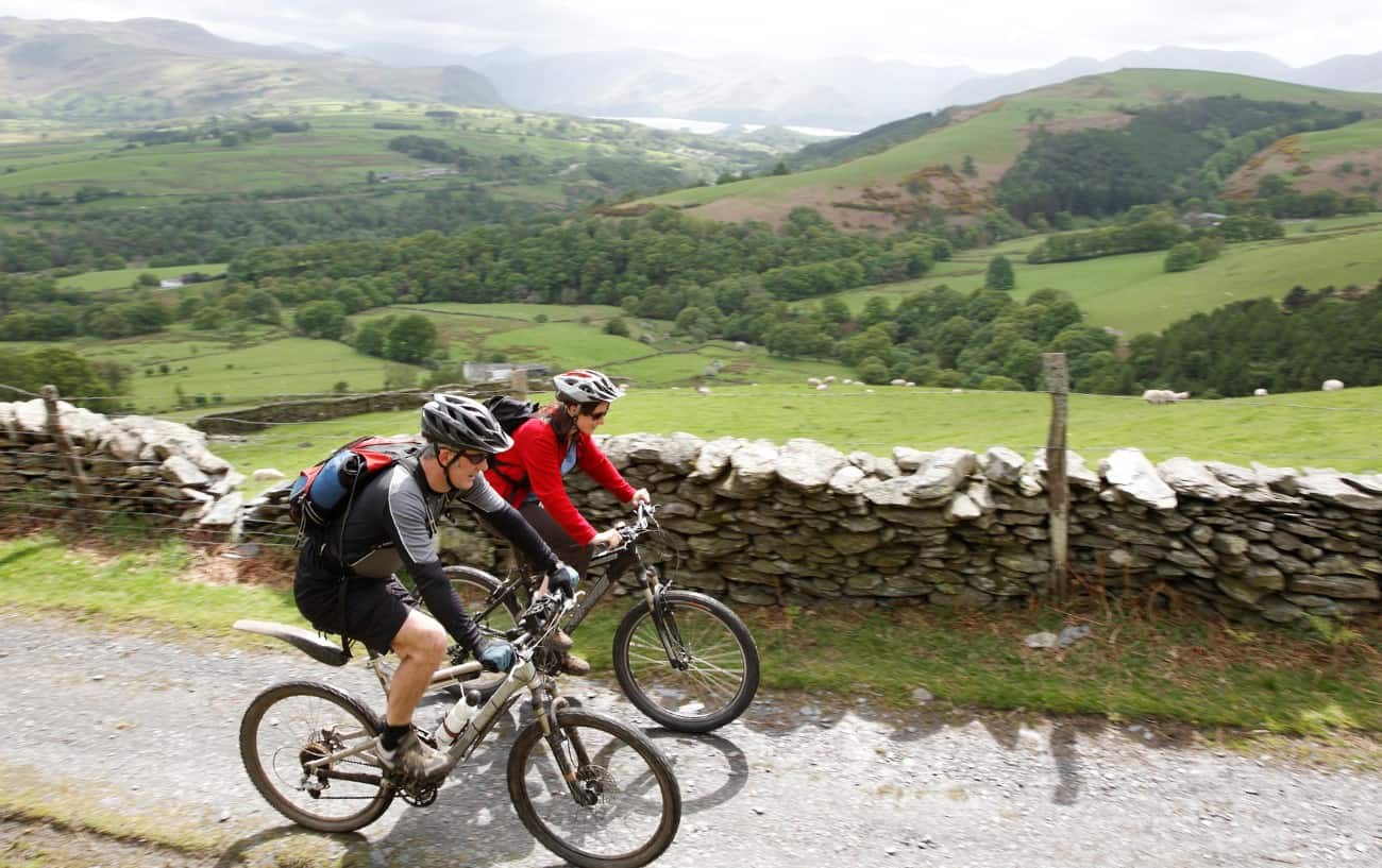 Two cyclists wearing helmets ride mountain bike through the Yorkshire countryside.