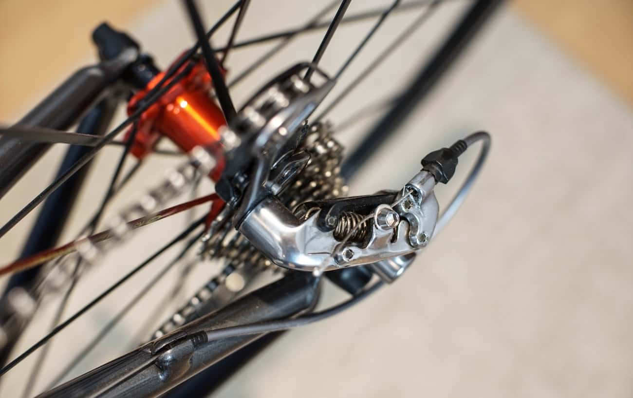 Close-up of a silver bike derailleur on the back wheel of a dark grey road bike.