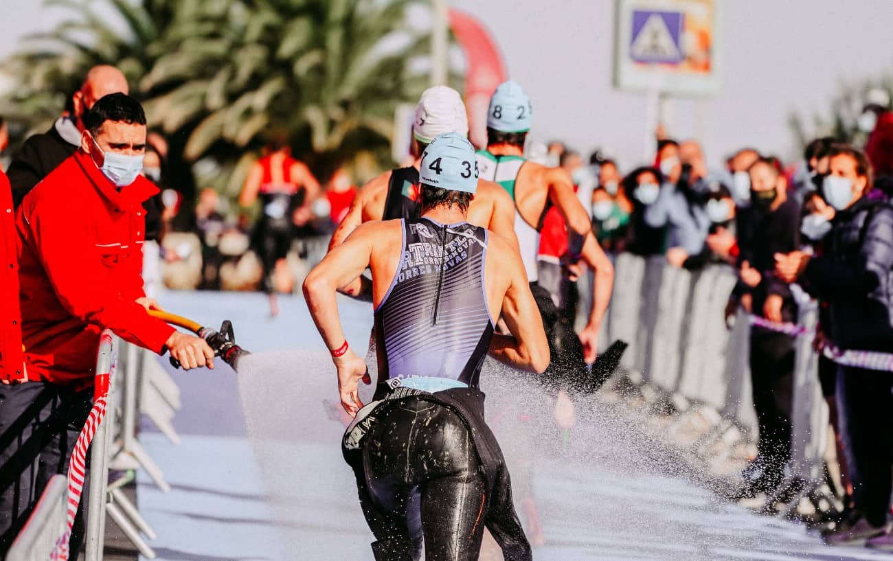 Three triathletes enter the transition zone during a race.