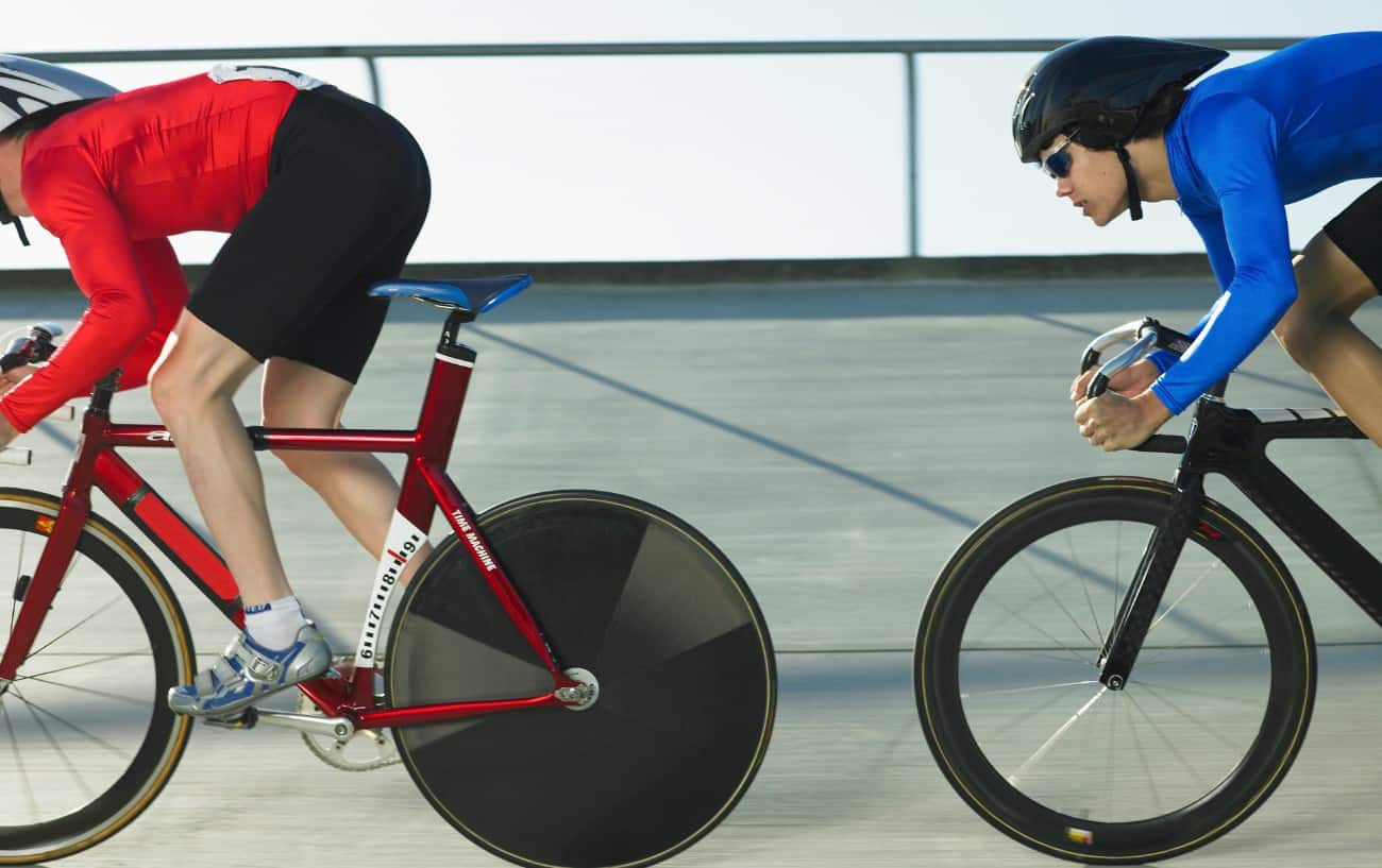Two cyclists pursue each other around a velodrome track.