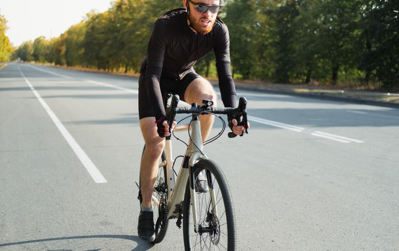 A cyclist rides a white gravel bike on the road.