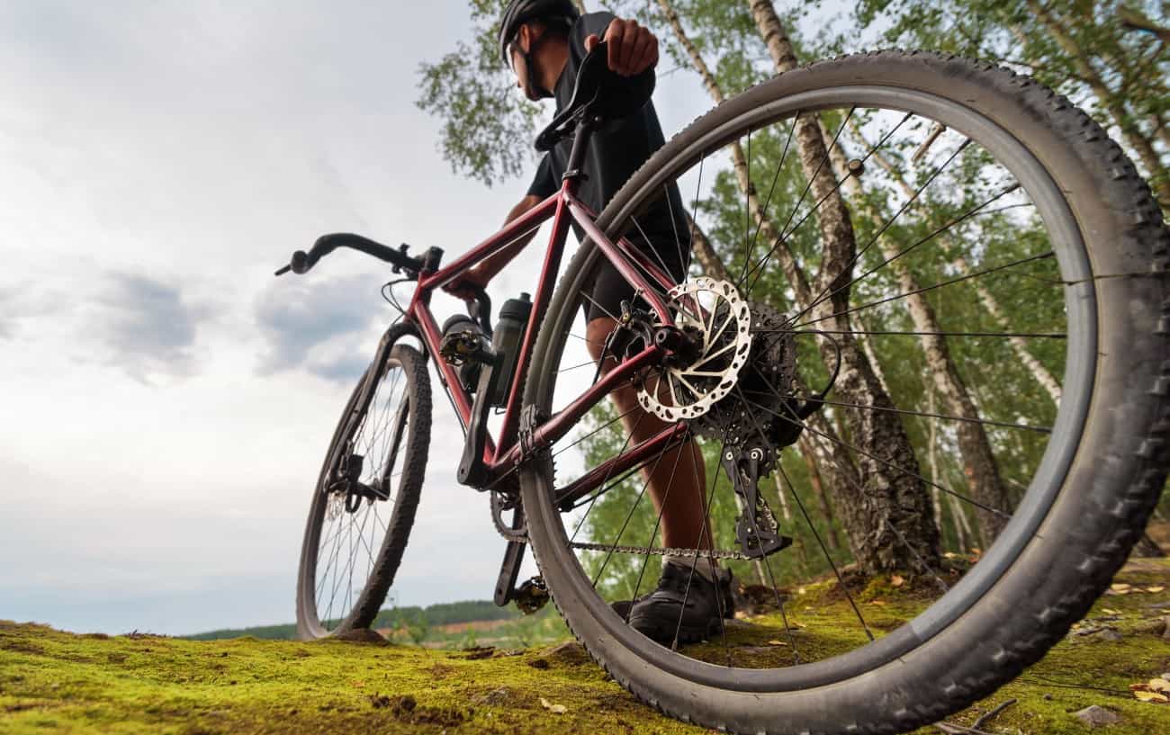A rider pauses on a grassy trail with his burgundy gravel bike.