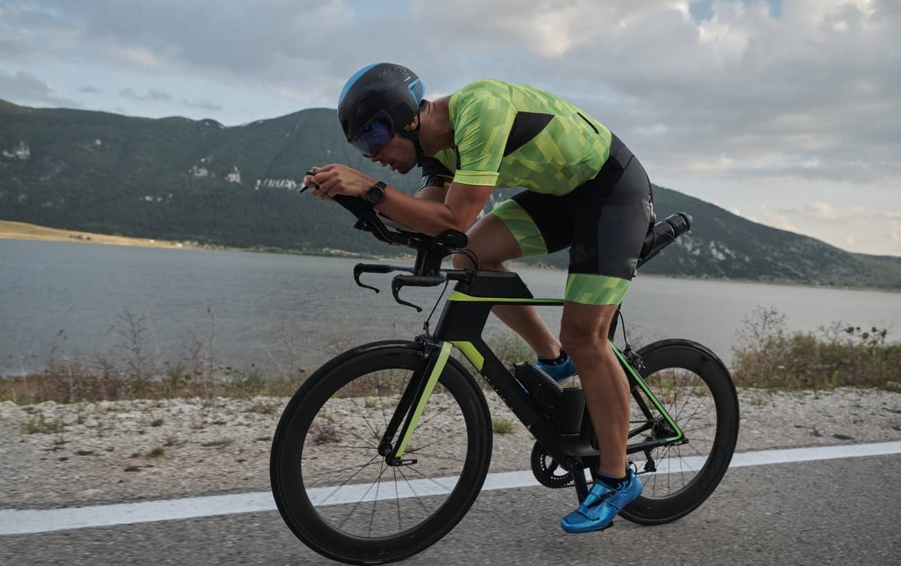 A cyclist in a green jersey rides a time-trial bike.