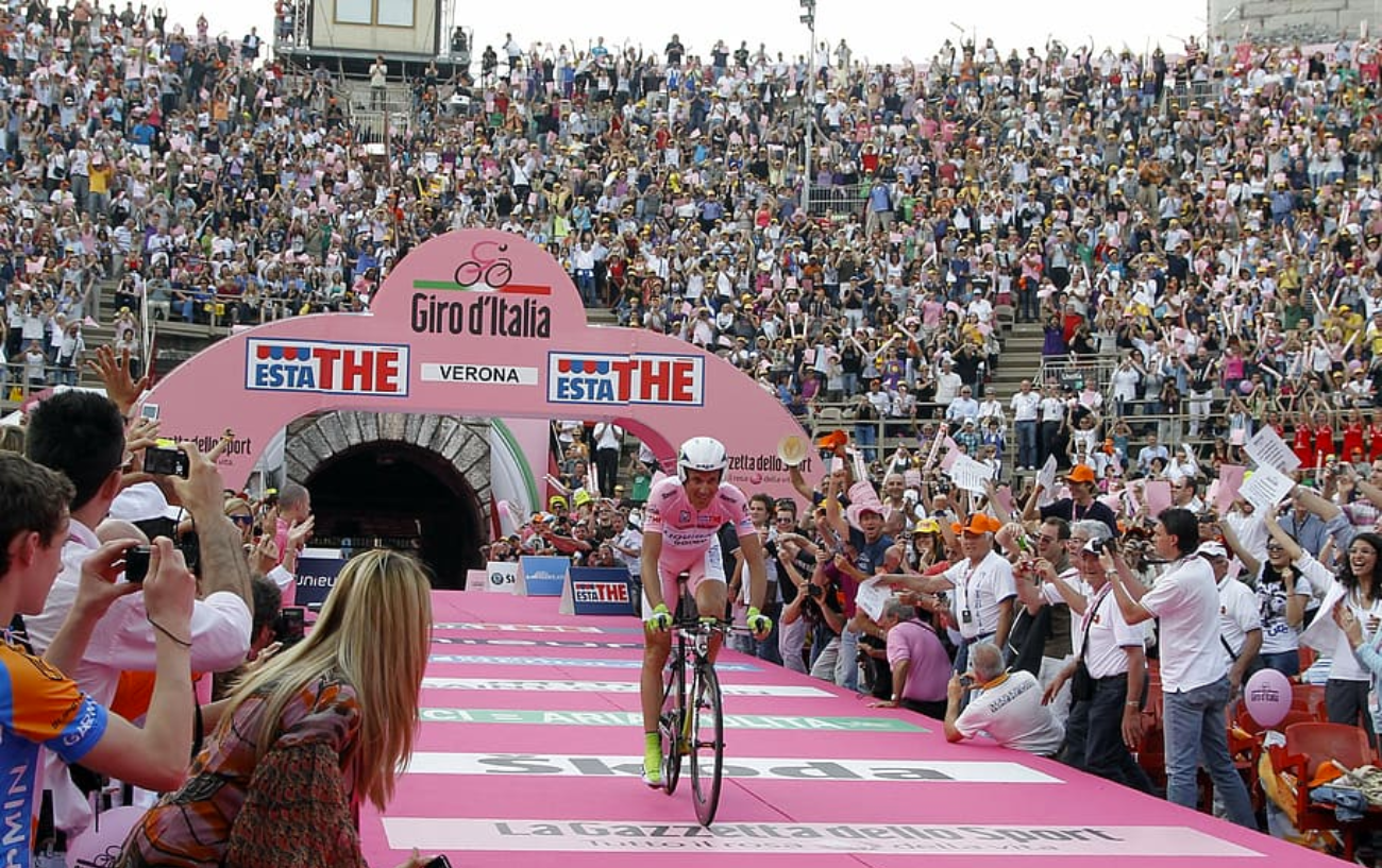 Giro d'Italia Jersey Guide: The Maglia Rosa holder cycles through a grandstand at the opening of a time trial stage.