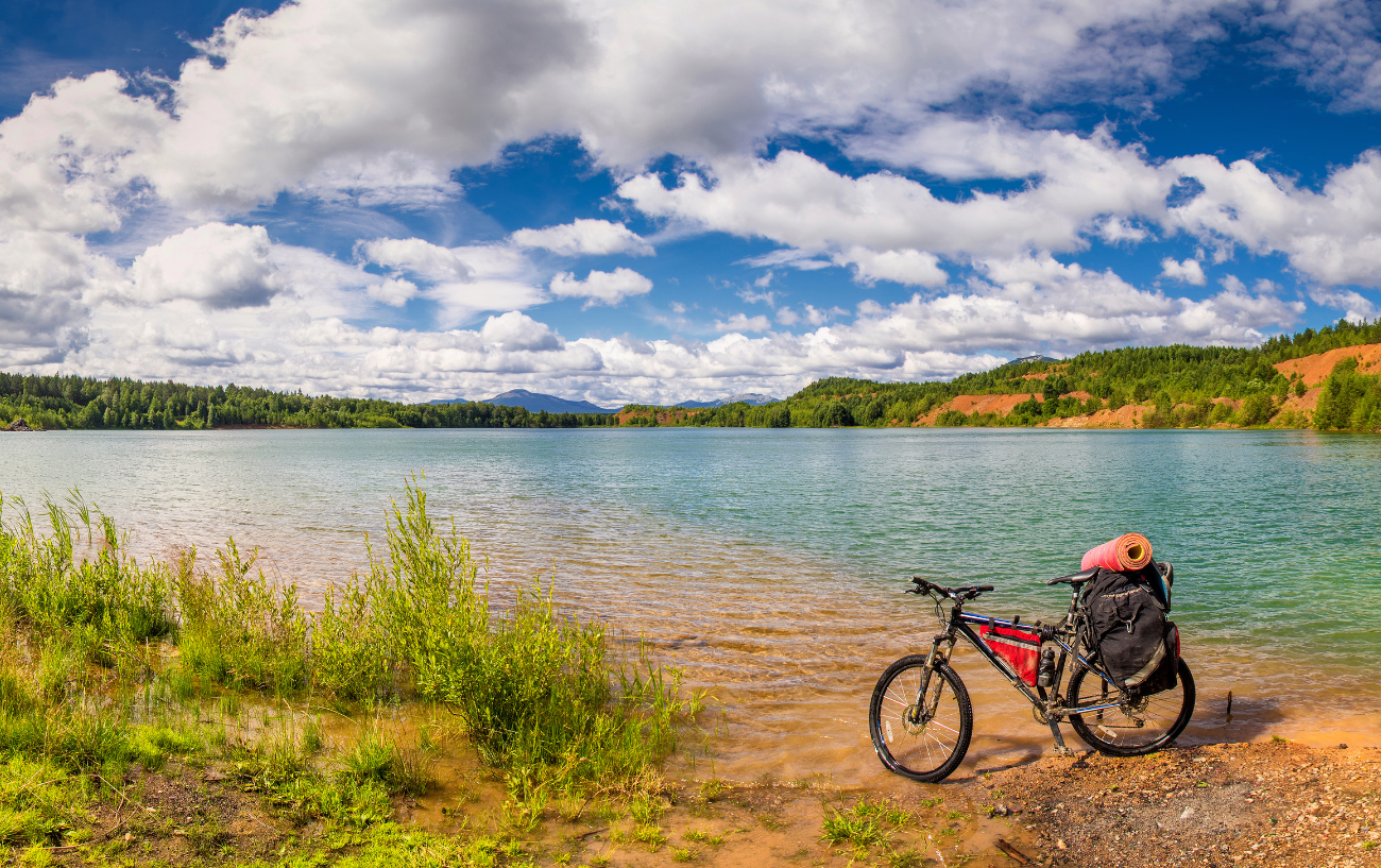 What is a touring bike? A black touring bike sits on the shore of a lake.