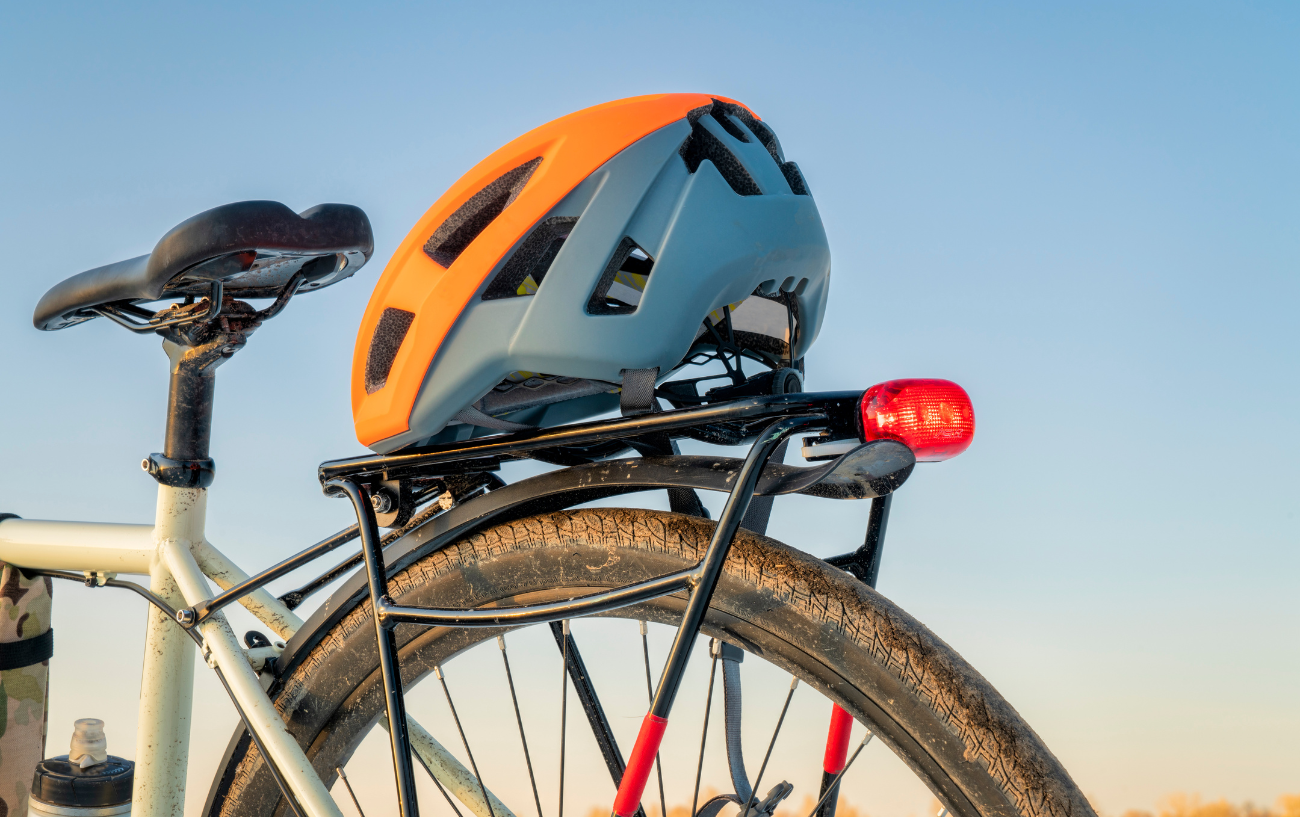 Close up of a helmet on the rear rack of a white touring bike.