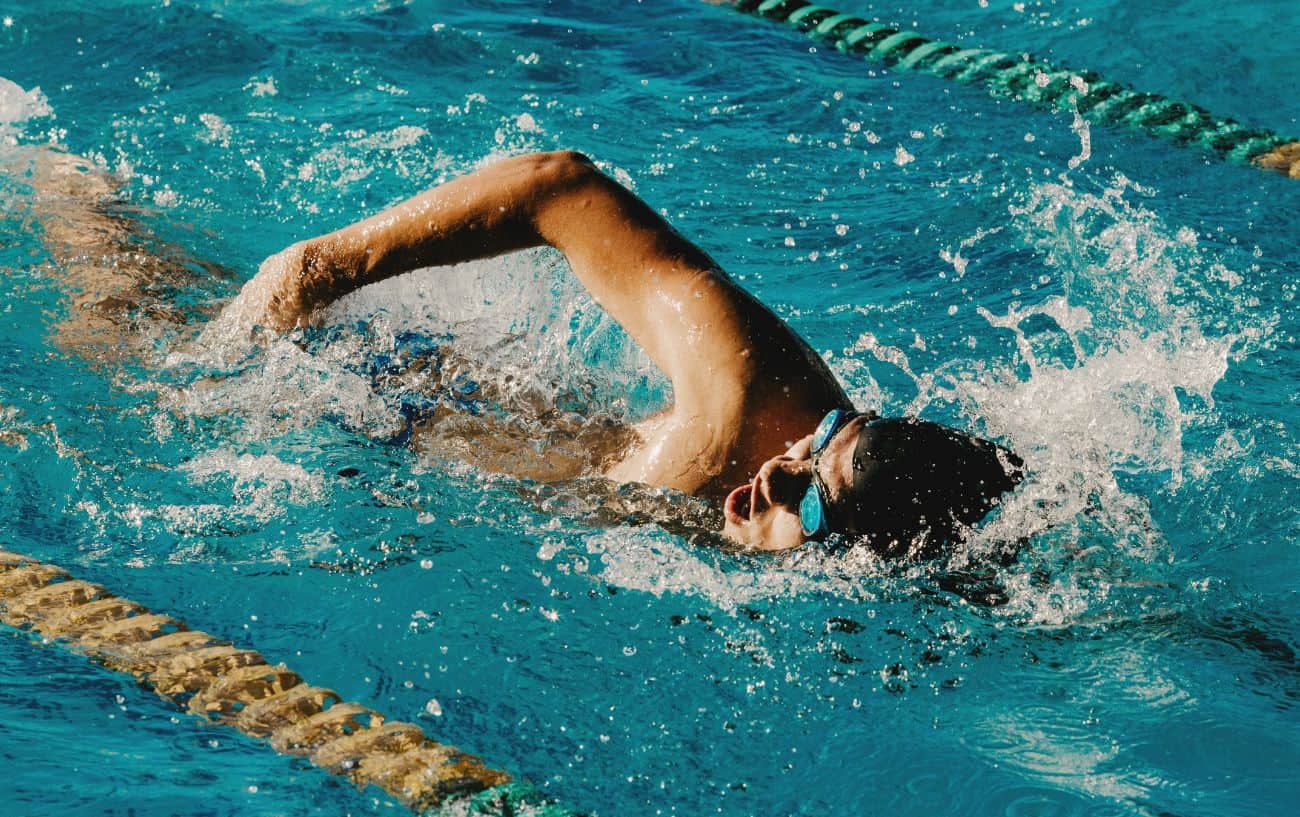 A man swims front crawl in a swimming pool.