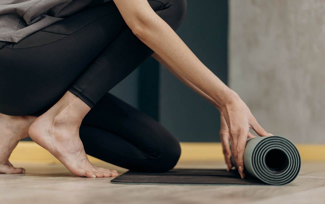 Close-up of a woman rolling out a grey yoga mat.