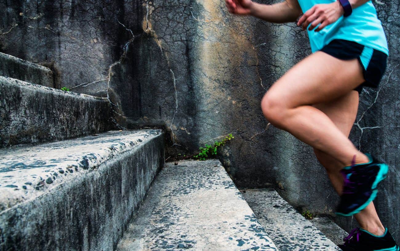 Close-up of a woman in blue running gear climbing a flight of stairs.