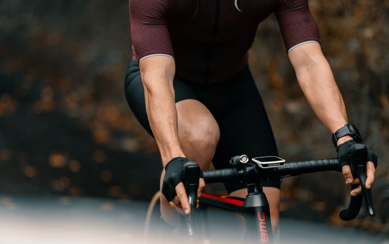 Close-up of a cyclist in a burgundy jersey riding a black BMC road bike.