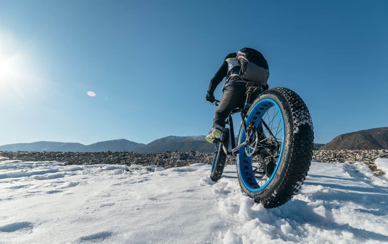 Close-up of the back wheel of a fat tire e-bike in a snowy landscape.