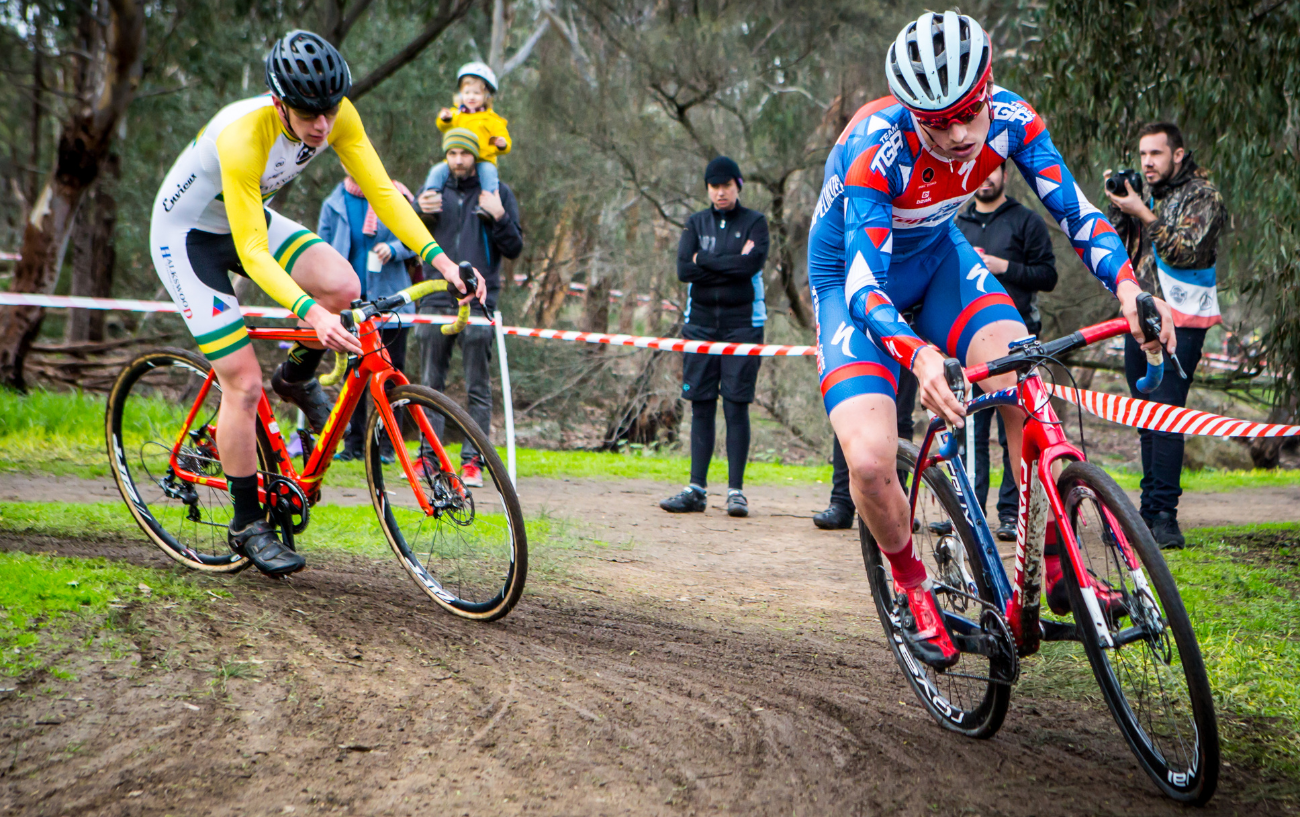 Two cyclocross riders attack a muddy bend.