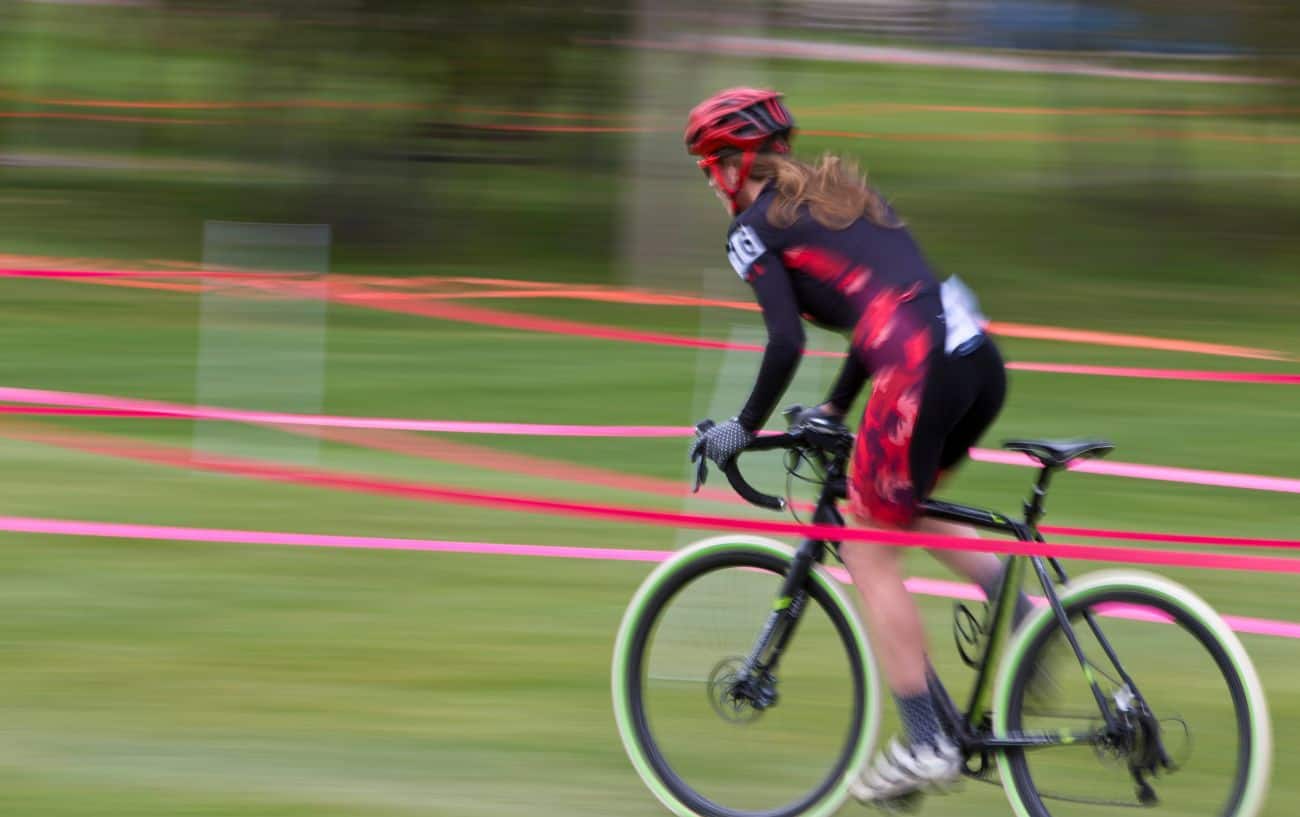 A cyclocross rider on a black bike speeds up a climb.
