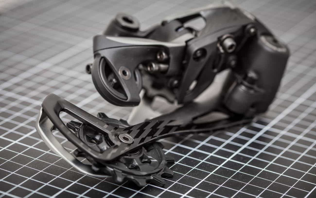 A black rear-derailleur sits on a checked background.